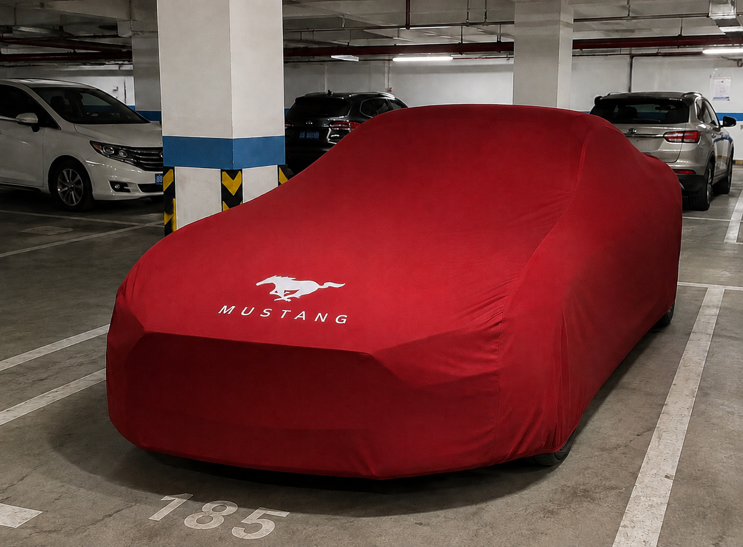 Ford Mustang covered with a red custom-tailored indoor car cover in a parking garage