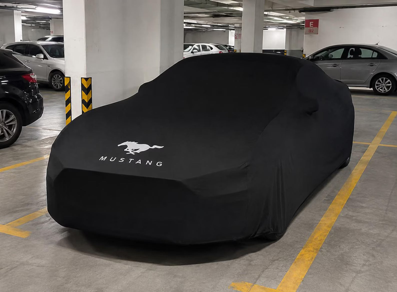 Ford Mustang fully protected with a black vehicle-specific indoor car cover in a garage