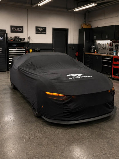 Ford Mustang with a black custom-fit indoor car cover partially removed, top view