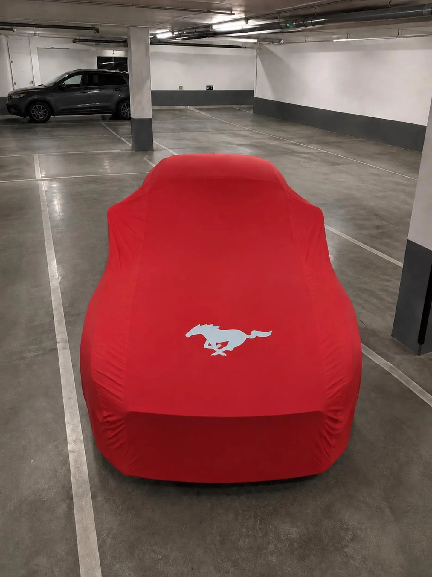 Ford Mustang protected by a red precision-fit indoor car cover, viewed from above
