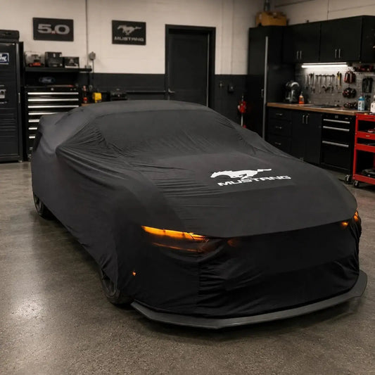 Ford Mustang with a black custom-fit indoor car cover partially removed, top view